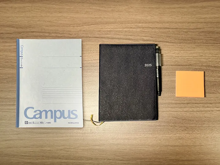 付箋型のメモとノート、ペンのついた黒い手帳の写真